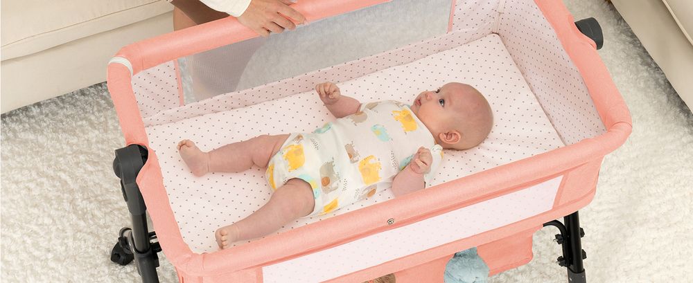 Baby resting in a Pink BCOL bassinet